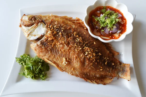 Kızarmış balık yemek masası üzerinde beyaz bir plaka ve dip sos üzerinde