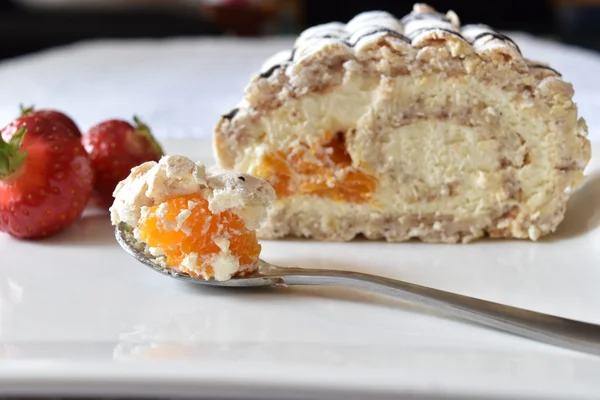 Meringue and hazelnut cake roll with whipped cream, chocolate and mandarins. Stock Image