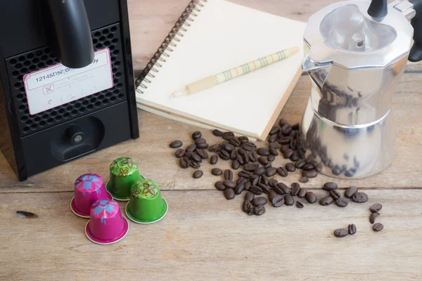 Cápsula Nespresso, cafetera y granos de café sobre fondo de madera . — Foto de Stock