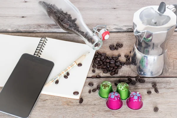 Кофейная капсула, кофеварка и кофейные зёрна на деревянном фоне . — стоковое фото