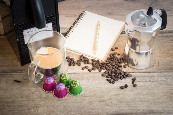 Nespresso kapsül, kahve makinesi ve kahve çekirdekleri ahşap arka plan üzerinde.