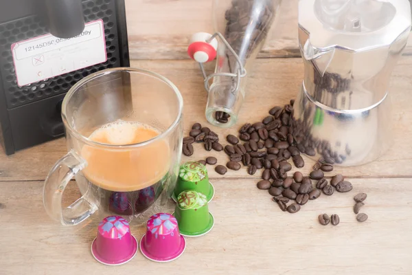 Taza de café expreso y cápsula con granos de café sobre mesa de madera . — Foto de Stock