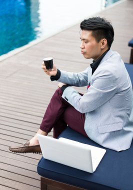 Dizüstü bilgisayar ile Yüzme havuzunda çalışan iş adamı.