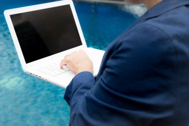 Dizüstü bilgisayar ile Yüzme havuzunda çalışan iş adamı.