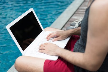 Dizüstü bilgisayar ile Yüzme havuzunda çalışan iş adamı.