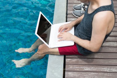 Dizüstü bilgisayar ile Yüzme havuzunda çalışan iş adamı.