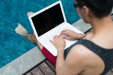 Dizüstü bilgisayar ile Yüzme havuzunda çalışan iş adamı.