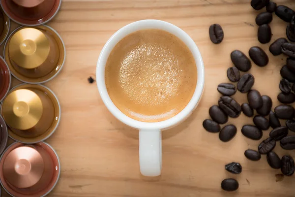 Cup of espresso with espresso  capsule and coffee beans.