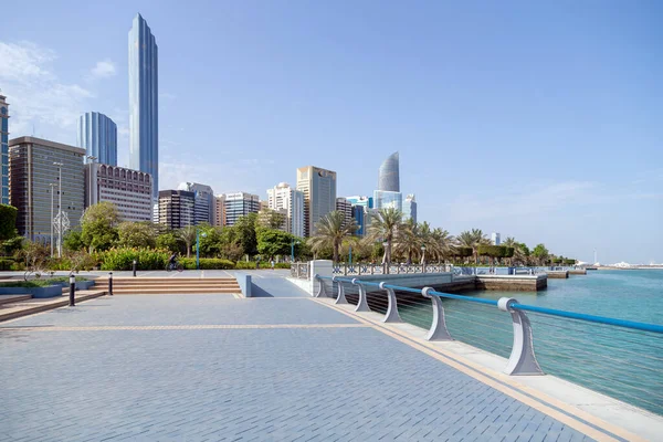 ABU DHABI, Emirados Árabes Unidos - 30 de abril de 2021: Abu Dhabi Corniche pela manhã. Pessoas caminhando à distância com modernos skyscapers no fundo. — Fotografia de Stock