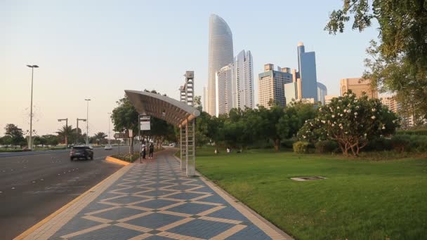 ABU DHABI, UAE - MAY 23, 2021: Bus stop in Abu Dhabi. Daily traffic during golden hour. People walking by. — Stok video