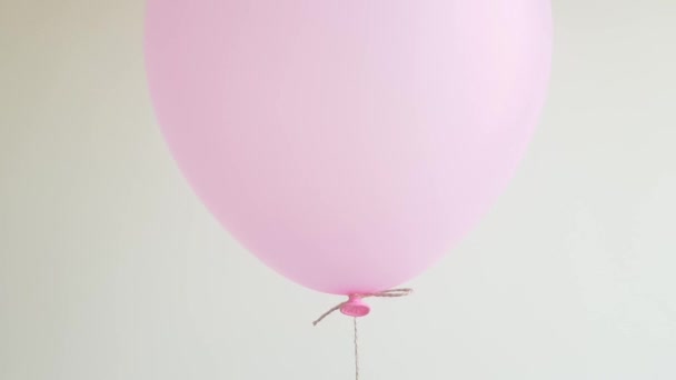 Light helium balloon in pink floating against off white wall, celebration, birthday concept. Closeup. — Stock Video