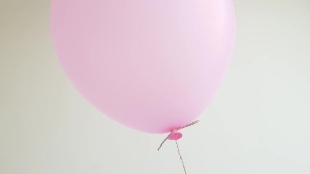 Világos hélium lufi rózsaszín lebegő off fehér fal, ünneplés, születésnapi koncepció. Közelkép. — Stock videók