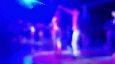 Gece kulübünde sahnenin odak noktasını kaybetmiş. Bokeh ışıkları ve dans eden siluetleri var.