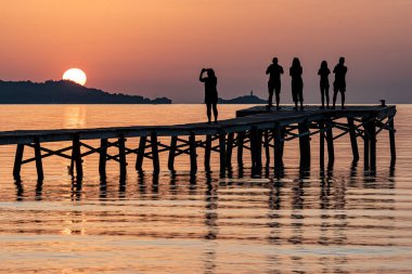İspanya 'da gün doğumu. Sabahın erken saatlerinde Mallorca 'daki Alcudia' da insanlar güneşin doğuşunu çekiyorlar. Fotoğraf Haziran 2025 'te çekildi..