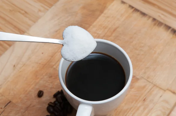 Taza de café con azúcar en una cuchara en forma de corazón — Foto de Stock