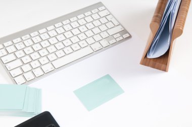 Bilgisayar klavyesi ve boş kartviziti olan beyaz ofis masası.