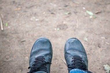 Eğitmen Ayakkabı çamurlu açık arka plan üzerinde erkek ayakları