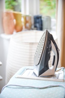 Ütü masasında ütü masasında ev içi bir odada.