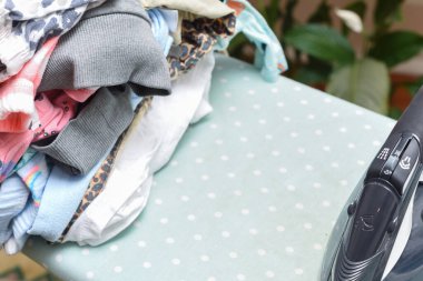 Ev işleri ve ev işleri ütülenecek bir yığın kıyafetle buhar ütüsü.