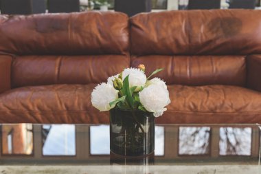 Şık bir odanın içindeki masanın üstünde suni çiçeklerden oluşan zarif bir buket.