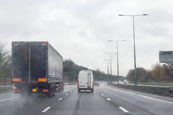 Transport cargo truck travelling down a busy road in rain the lorry has no logo