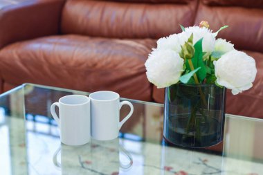 İki fincan çay ya da kahve hafif bir evde, bir sehpanın üzerinde yan yana.