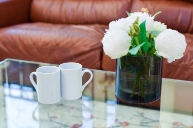 İki fincan çay ya da kahve hafif bir evde, bir sehpanın üzerinde yan yana.