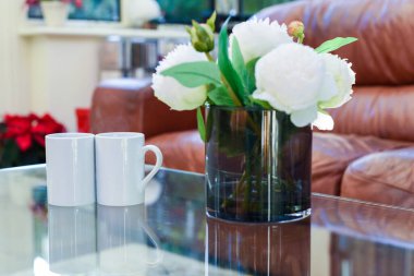 İki fincan çay ya da kahve hafif bir evde, bir sehpanın üzerinde yan yana.