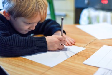 Çocuk ev hapsi sırasında mutfak masasında ödev yapıyor.