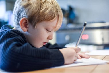 Çocuk ev hapsi sırasında mutfak masasında ödev yapıyor.