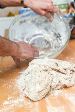 Ev mutfağında ekmek yapan kişi hamur yapmak için malzeme ekliyor.
