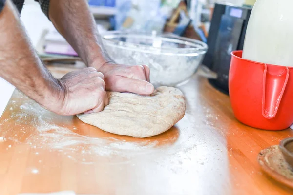 Person making bread in a home kitchen adding ingredients to make the dough and then kneading it by hand