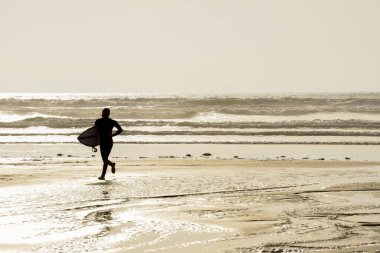 Sörfçüler sahilde, sörf yaparken fısıldıyorlar.