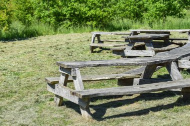 Güneşli bir parkta büyük bir piknik masası ve bank.