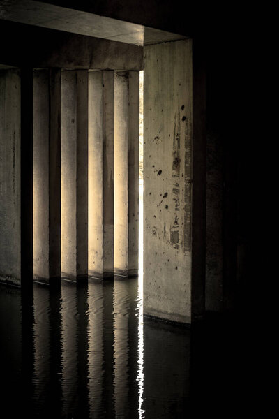 Concrete pillars of a brigde reflect in rippling river water