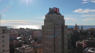 İtalya 'nın Cenova kentinde binanın tepesinde büyük bir ekranın yer aldığı bir gökdeleni gösteren etkileyici bir hava görüntüsü. Bu şehir sahnesinde şehrin kalbinde modern mimari ve dinamik dijital reklamlar sergileniyor..