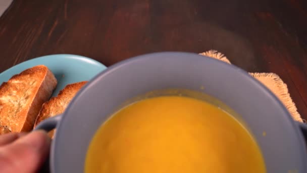 A woman's hand puts a bowl of homemade orange pumpkin soup on a table. Healthy diet. Toasted bread. — Stock Footage Woman Hand Puts Bowl Homemade Orange Pumpkin Soup Table Healthy Stock Footage