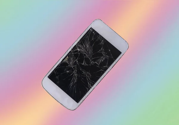 Broken mobile phone with cracked display on neon background, flat lay.