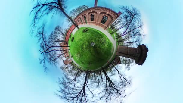 Červené cihly Archs Tower alej v Green parku vr Video 360 malé planety Video čerstvá tráva zelená trávník dlažební kameny budov jsou za holé rozvětvené stromy — Stock video