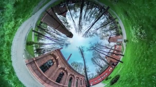 Tijolos vermelhos Arcos beco no parque verde vr vídeo 360 pequeno planeta vídeo grama fresca gramado verde pavimentação pedras edifícios estão por trás de árvores ramificadas nuas — Vídeo de Stock