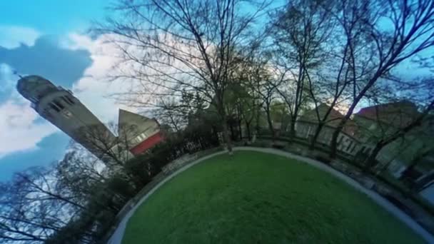 Люди в переулке в Грин-Парке vr Видео 360 Little Planet Видео Здания башня Свежая трава Зеленая лужайка Здания за деревьями его становится темным в парке — стоковое видео