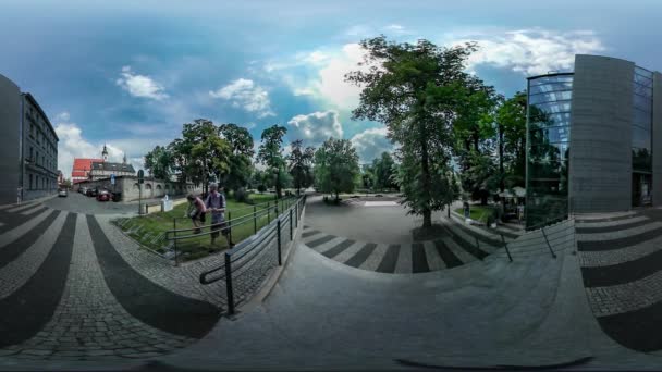 Vídeo 360Vr Pai Filha Dia da Cidade Opole Pessoas em uma Praça da Cidade Pavimento Pedras Edifício moderno Carros estacionados Árvores verdes Pessoas têm um descanso no dia ensolarado — Vídeo de Stock