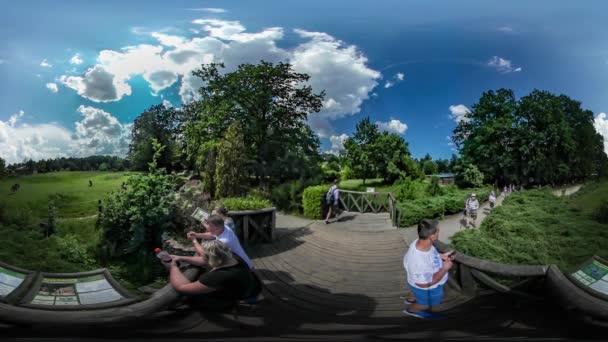 360vr Video familjer utflykt på Zoo Opole promenader i parken tittar bakom planket på gröna träd gräsmatta mamma ser efter barn solig dag — Stockvideo