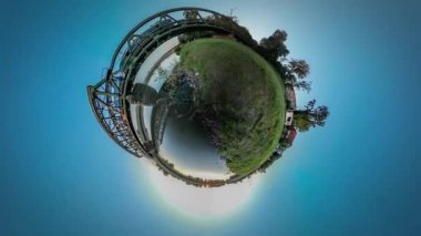 360vr Video tren sürme bitti Nehri Köprüsü evler köy tarafından banka Metal köprü beton destekler yeşil yamaçları günbatımı mavi gökyüzü yaz güneşli bir günde olduğunu