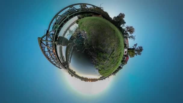 360vr Video vlak je na koni přes řeku most domy vesnice na bankovní Metal Bridge konkrétní podporuje zelené svahy Sunset Blue Sky letní slunečný den — Stock video