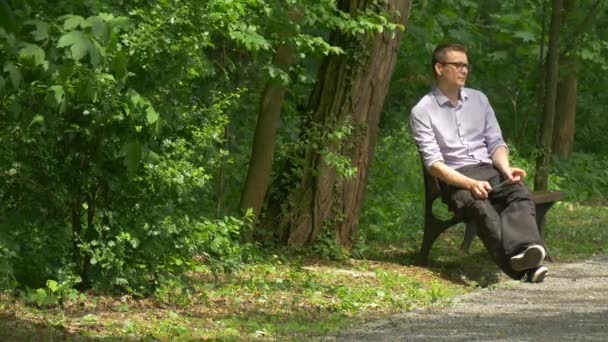 Man Sitting With Tablet in Park Clicks the Device on Bench Chatting Forex Imóveis Comprar Compras na Internet Passe um tempo na natureza Árvores verdes frescas — Vídeo de Stock