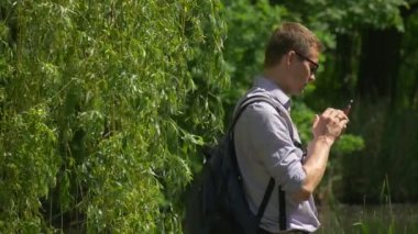 Birini Backpacker doğa taze zaman harcıyor yeşil arıyorsunuz bir cep telefonu ağaçlar göl su dalları güneşli yaz günü sallanan adam tıklama
