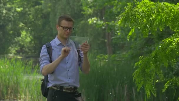 Backpacker Clicks Virtual Tablet in Park Walks Away Forex Internet Shopping Chat Empresario pasa tiempo en la naturaleza Árboles verdes frescos Soleado día de verano — Vídeo de stock