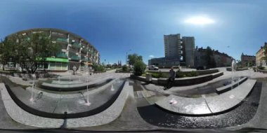 360vr Video turist adam, Çeşme Backpacker Cityscape otomobil tahrik edilmektedir yol Multi-Storeyed evler güneş parlar mavi gökyüzü yeşil ağaçların yanında oturuyor
