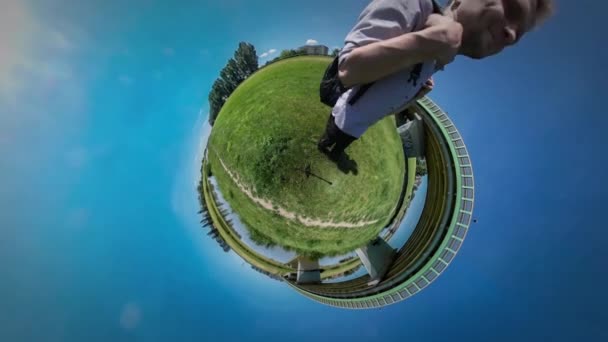 360Vr Video Man Has Fun Shows His Biceps Walking by Green Lawn Bridge Through River Reed by the Water Tourist at the Nature Sunny Summer Midday Blue Sky — Stock Video